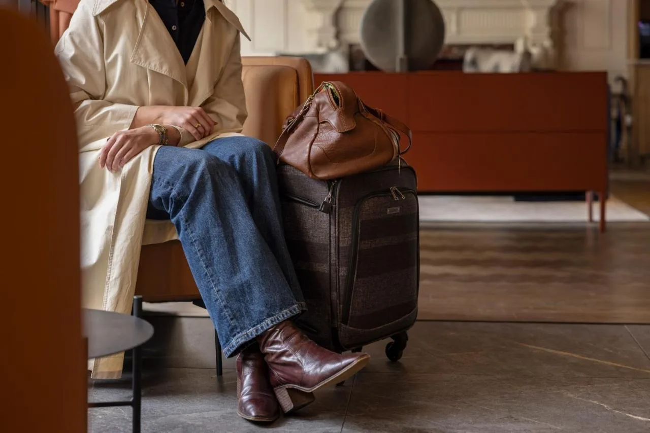a woman sitting in a chair with a suitcase at Apex Waterloo Place Hotel in Edinburgh
