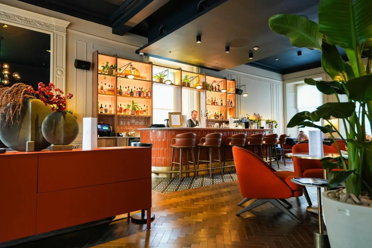 a bar in a restaurant with a man sitting at the bar at Apex Waterloo Place Hotel in Edinburgh